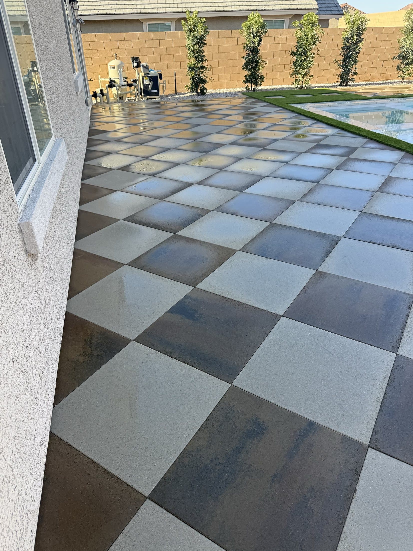 Checkerboard paver patio extending along the back of the home