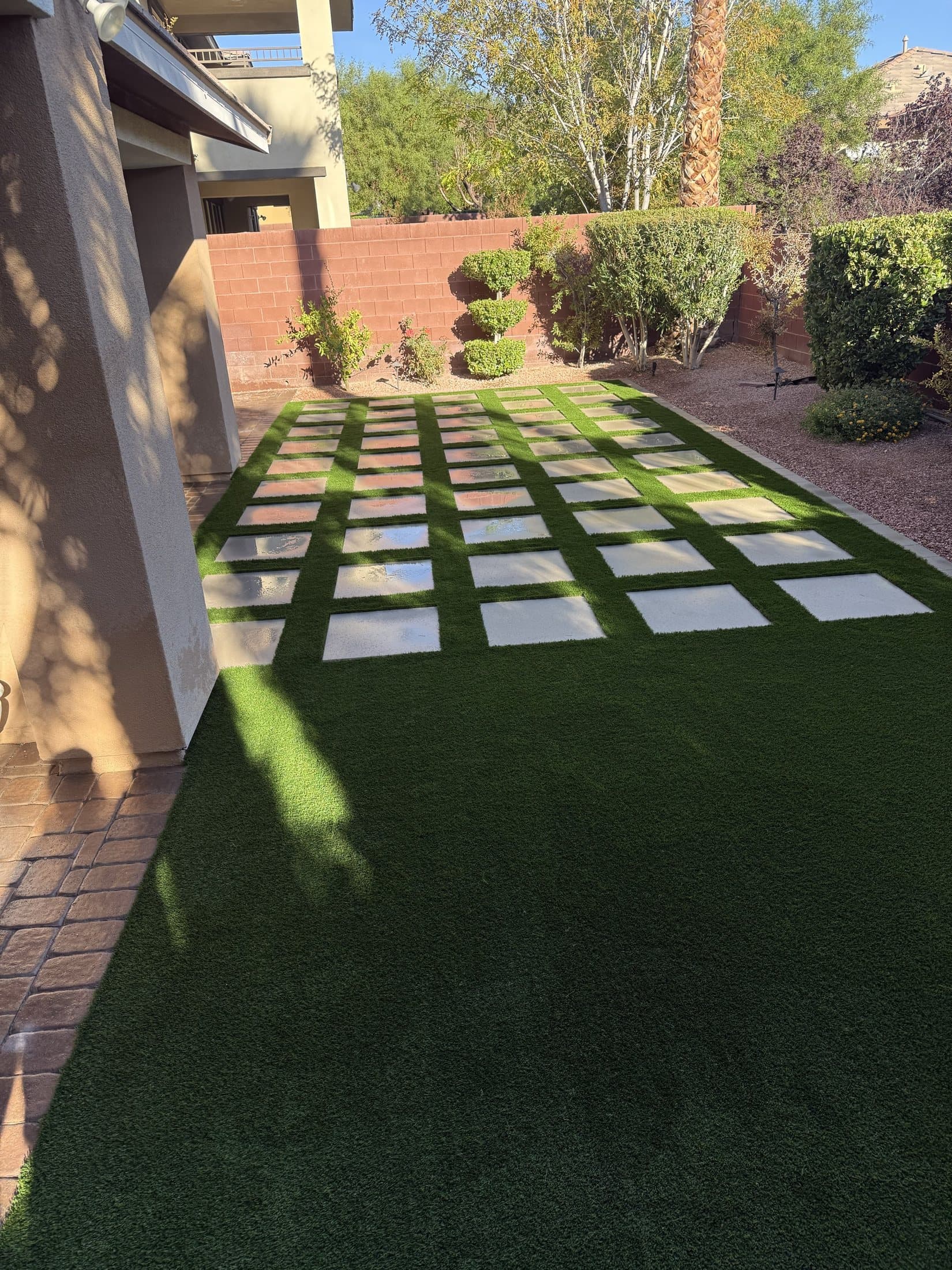 Checkerboard paver-and-turf patio along the side yard